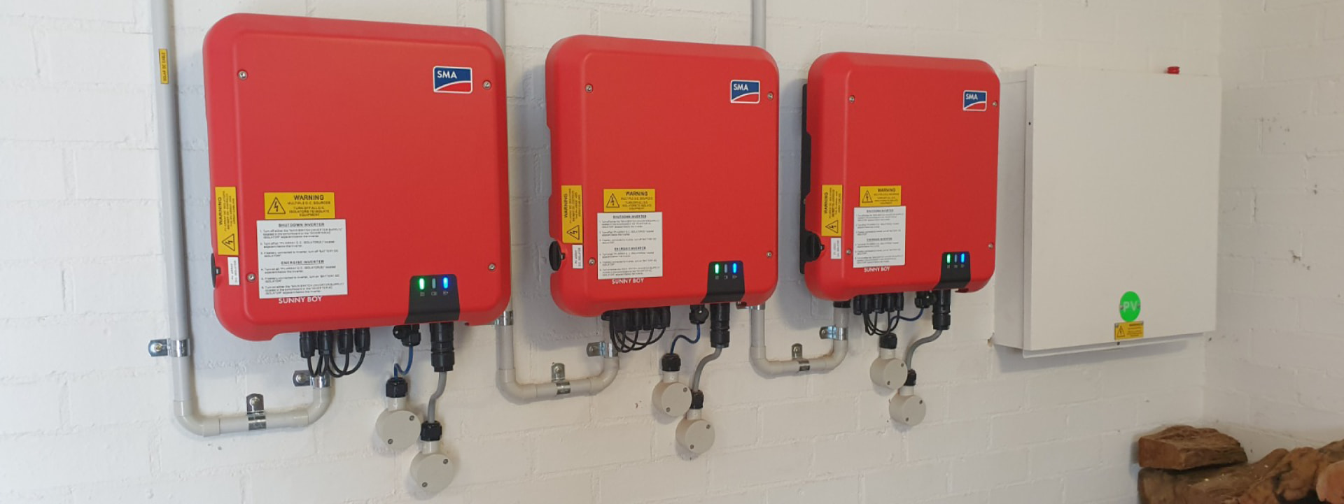 Three red SMA Sunny Boy inverters mounted on wall