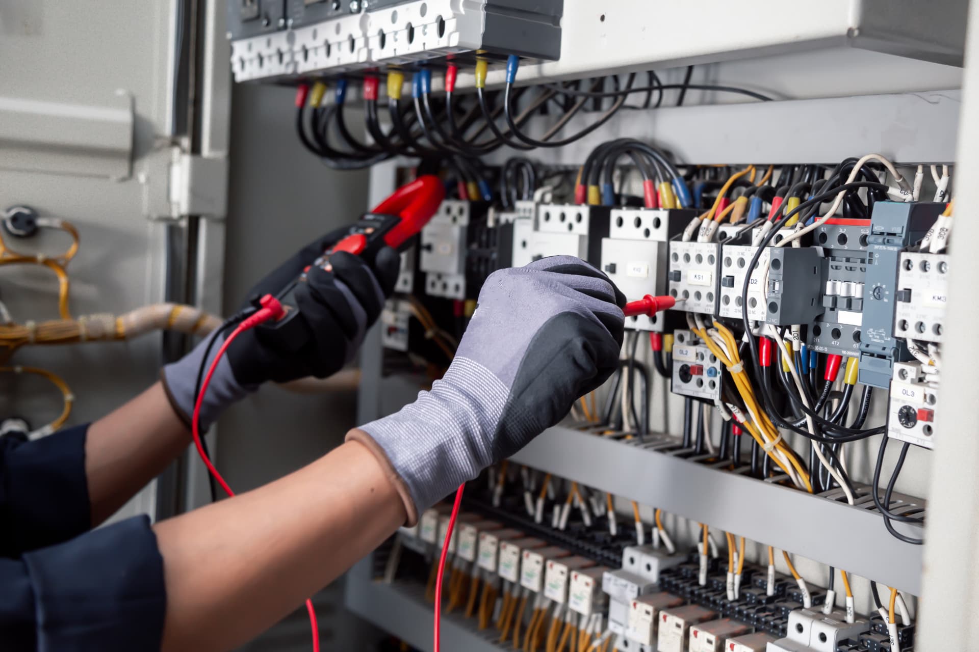 Electrician testing industrial control panel wiring with a multimeter