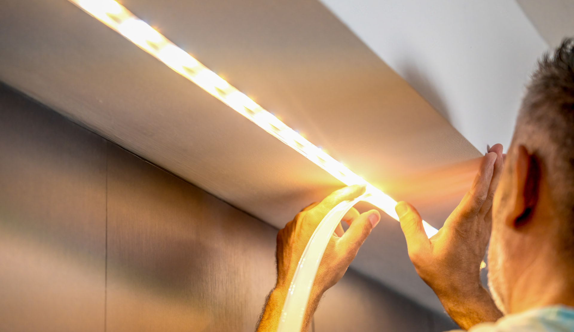 Electrician installing LED strip lighting under a cabinet